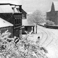 Foto Winter 1962: Rechts das Schulgebäude noch mit Mauer (dahinter Schulgarten) und einem Fenster (heute Relief); links das Burgheiligenhäuschen (1972 abgerissen)